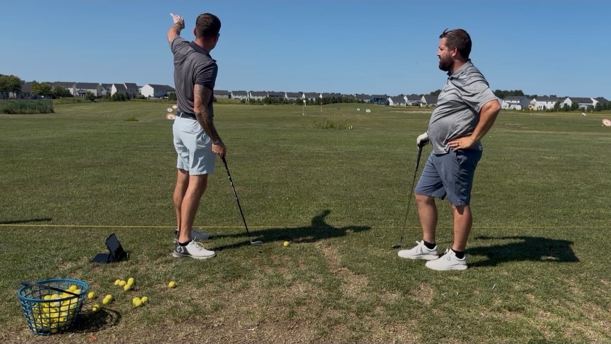 Colin Coughlin pointing down the range while a student listens during a lesson